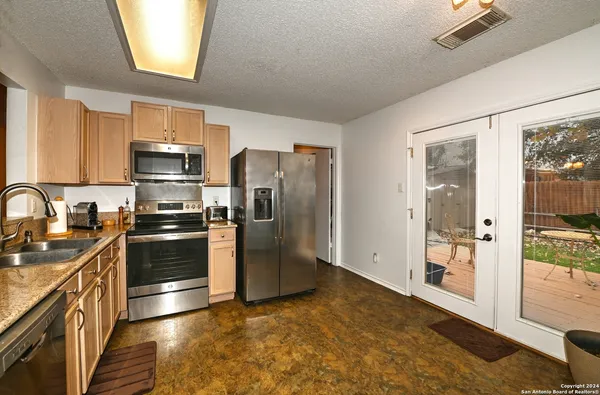 a kitchen with granite countertop a refrigerator and a stove top oven