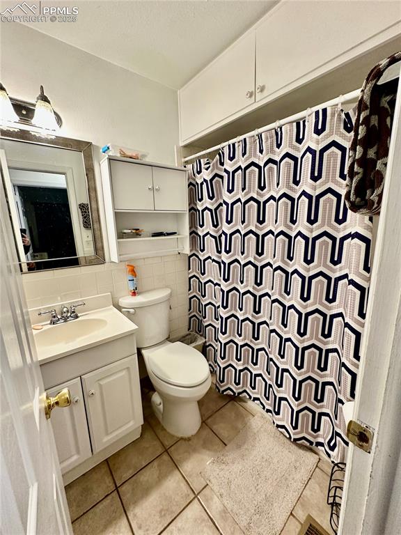 1701 Jerry Murphy Road Pueblo, CO 81001 - Photo 15 of 20 Full bathroom featuring tile walls, tile patterned floors, vanity, toilet, and a shower with shower curtain