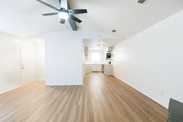 an empty room with wooden floor and ceiling fan