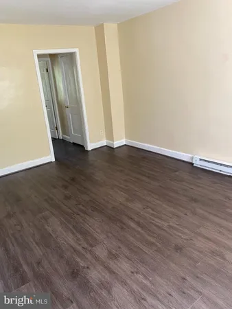 a view of an empty room with wooden floor and entrance