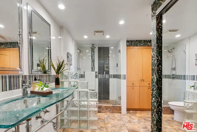 a bathroom with a granite countertop sink a toilet a mirror and shower