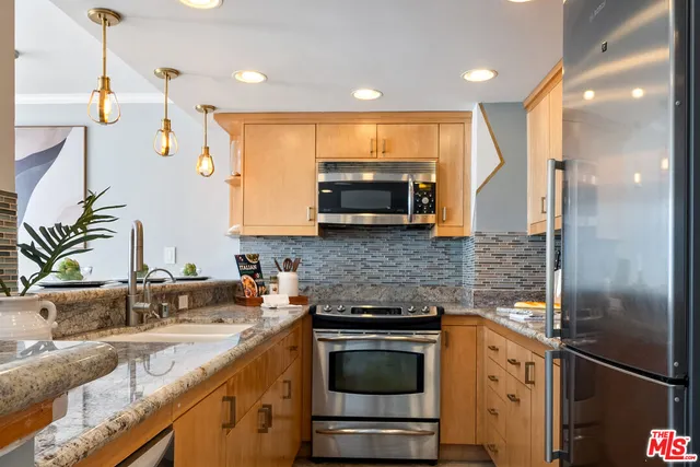 a kitchen with stainless steel appliances granite countertop a sink a stove and a refrigerator