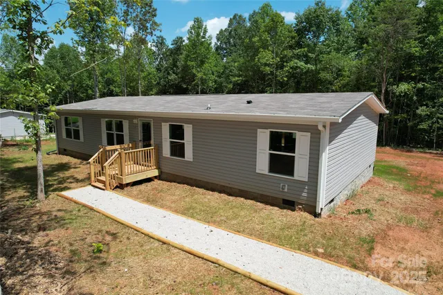 a view of a house with backyard and trees in the background