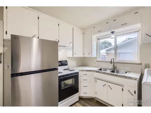 a kitchen with a sink a refrigerator a window and cabinets