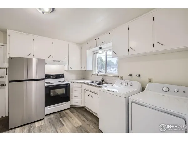 a kitchen with a sink a refrigerator and white cabinets
