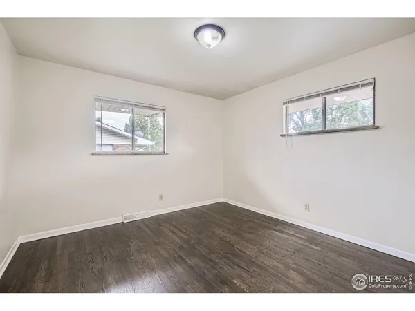 an empty room with wooden floor and window