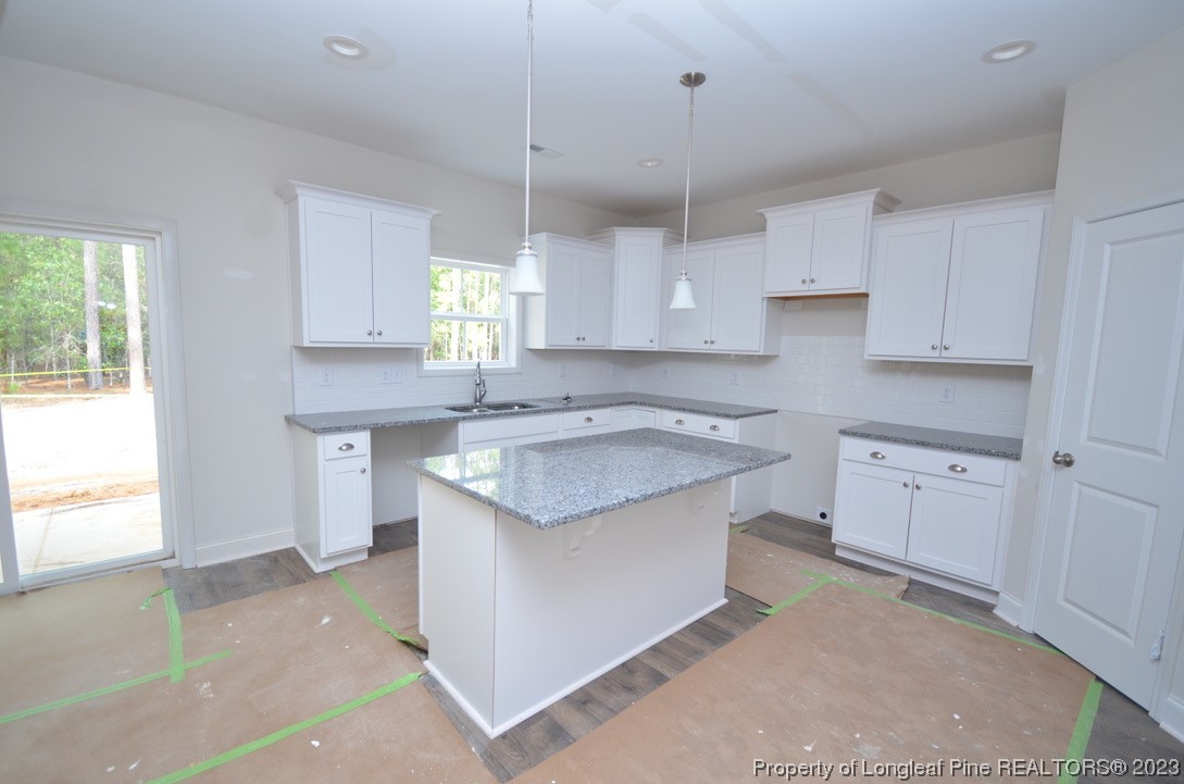 822 Quewhiffle Road Aberdeen, NC 28315 - Photo 5 of 7 a kitchen with granite countertop a sink stove a window and white cabinets