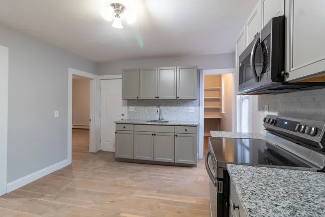 a kitchen with granite countertop a sink cabinets stainless steel appliances and a counter top space