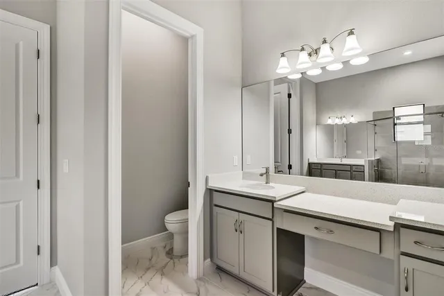 a view of bathroom with a sink and mirror with toilet