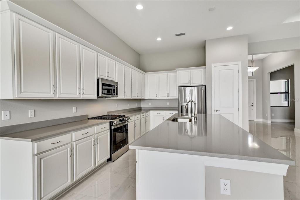 4533 Mondrian Court Sarasota, FL 34240 - Photo 10 of 49 a kitchen with kitchen island granite countertop a sink a stove and refrigerator