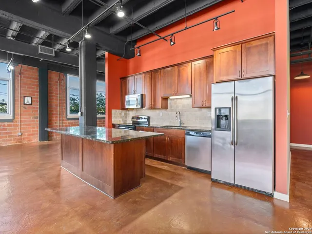 a kitchen with stainless steel appliances granite countertop a refrigerator and a stove