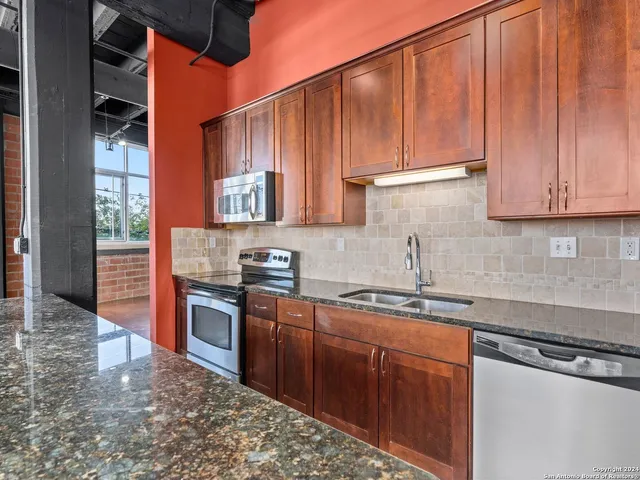 a kitchen with stainless steel appliances granite countertop a sink stove and cabinets
