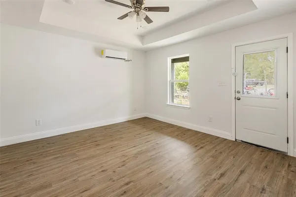a view of an empty room with wooden floor and a window