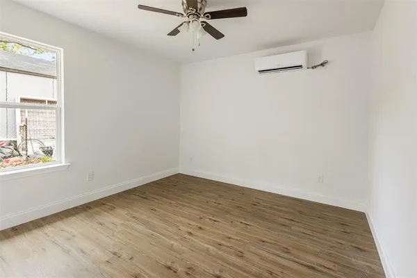 an empty room with wooden floor fan and windows
