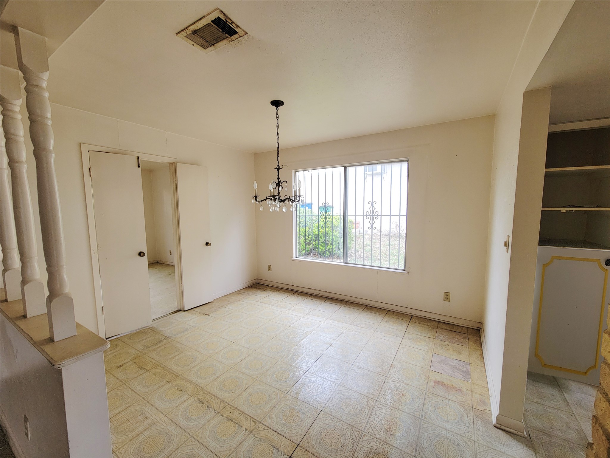 6605 Highpoint Drive Austin, TX 78723 - Photo 5 of 11 Open-concept room featuring tile flooring, a window with security bars, and an overhead chandelier