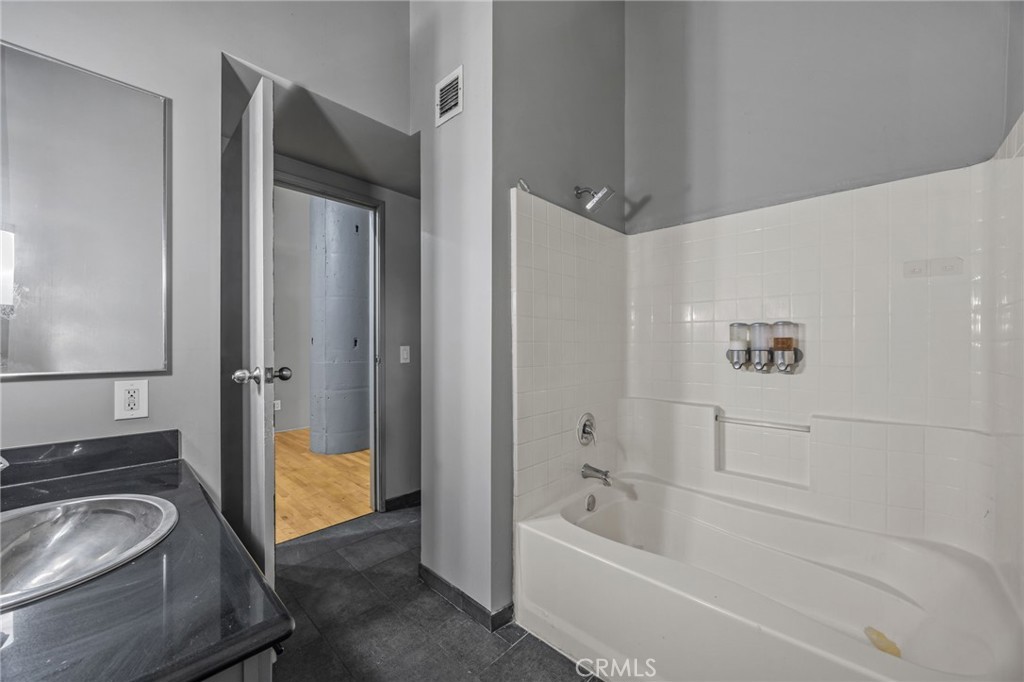 420 San Pedro Street, Unit 218 Los Angeles, CA 90013 - Photo 16 of 27 a bathroom with a granite countertop tub sink and mirror
