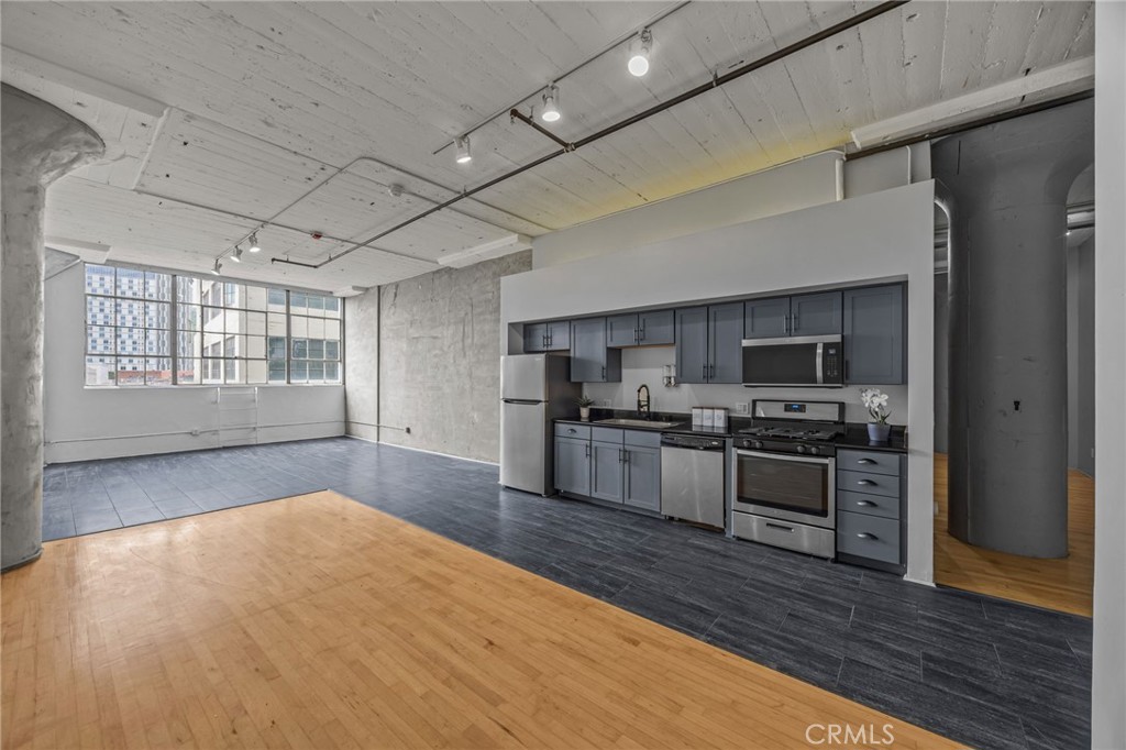 420 San Pedro Street, Unit 218 Los Angeles, CA 90013 - Photo 6 of 27 a large kitchen with stainless steel appliances wooden floors and wooden cabinets