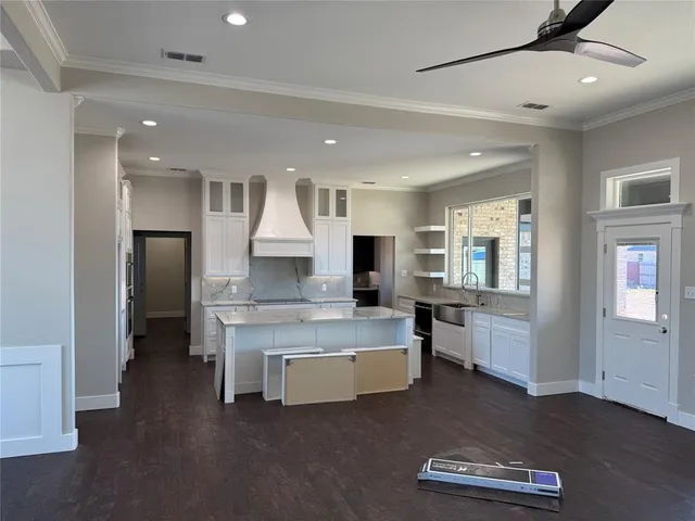 a large white kitchen with a large window appliances and cabinets