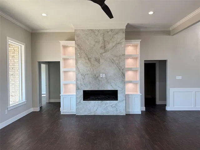an empty room with wooden floor fireplace and windows