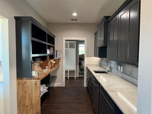 an empty room with wooden floor cabinet and windows