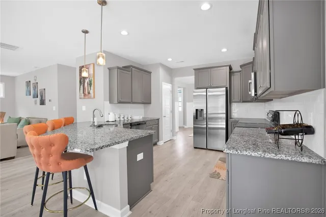 a kitchen with stainless steel appliances granite countertop a sink a stove a refrigerator and island with wooden floor