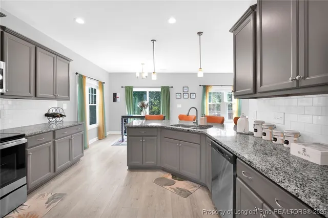 a kitchen with stainless steel appliances granite countertop a sink dishwasher stove and refrigerator with wooden floor