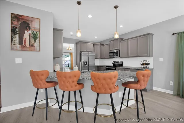 a kitchen with stainless steel appliances granite countertop a dining table chairs and a refrigerator