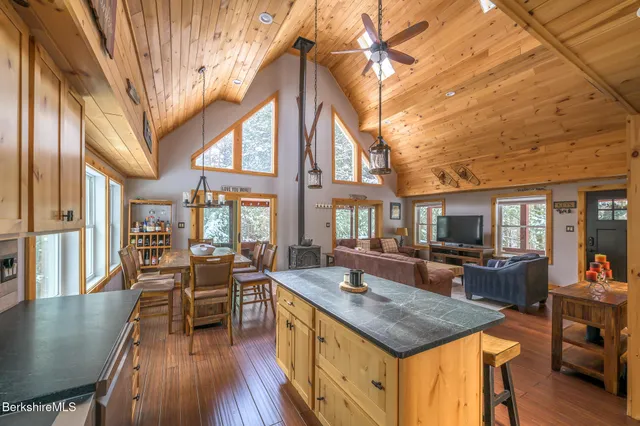 a living room with stainless steel appliances granite countertop furniture a couch a dining table and a large window