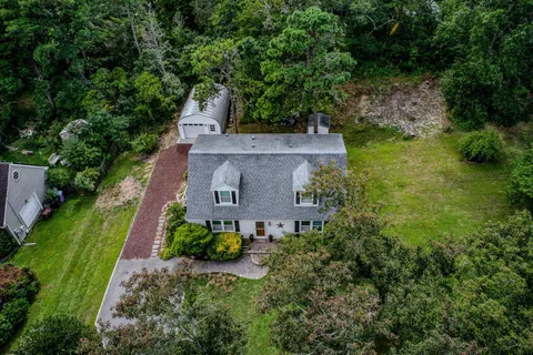 an aerial view of residential houses with outdoor space and trees