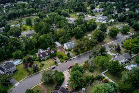 an aerial view of residential houses with outdoor space and trees