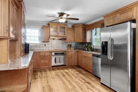 a white kitchen with stainless steel appliances granite countertop a sink a stove and a refrigerator