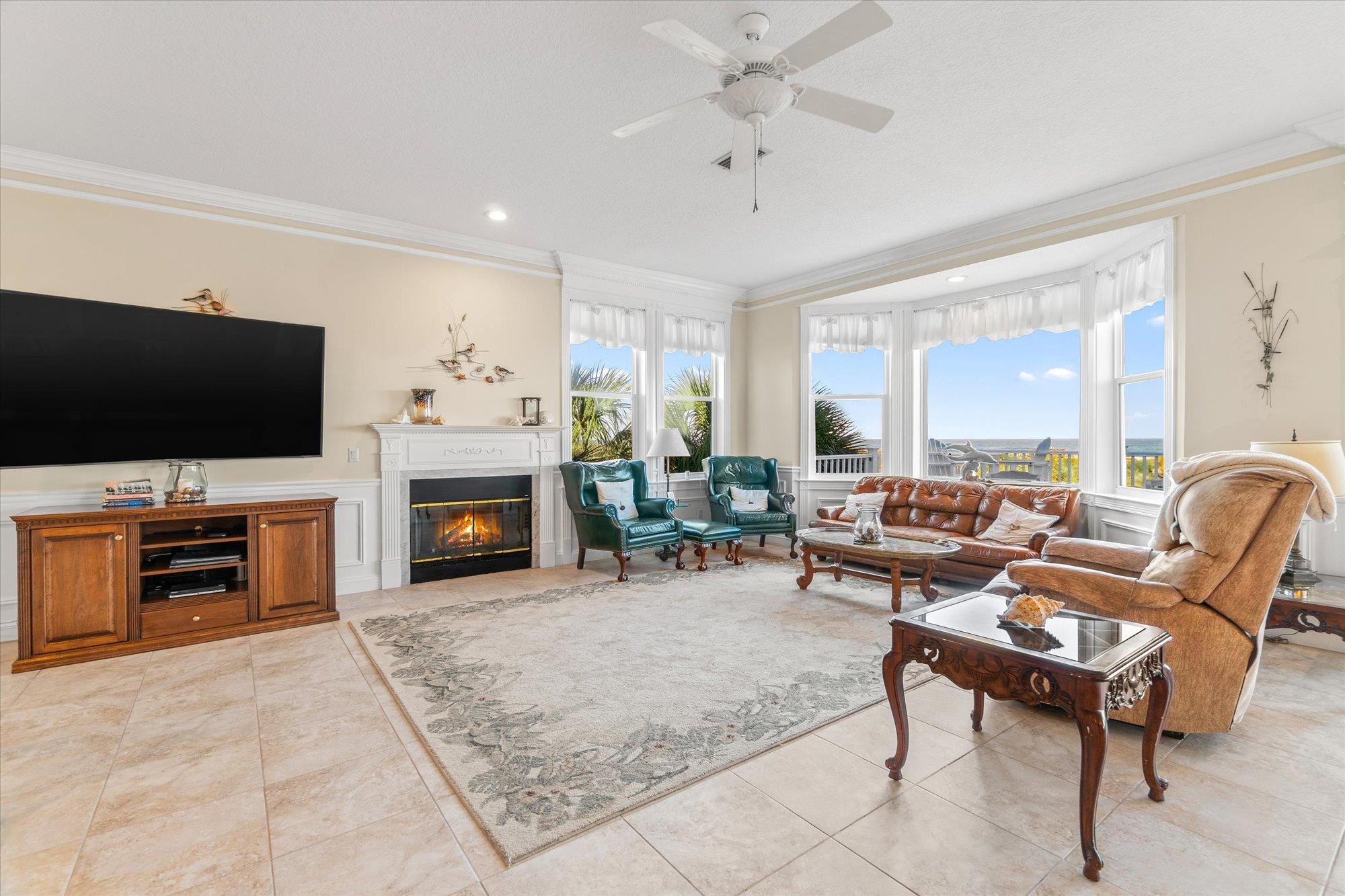5042 Atlantic View St. Augustine, FL 32080 - Photo 8 of 72 Living room featuring a glass covered fireplace, ornamental molding, plenty of natural light, a wainscoted wall, and a ceiling fan