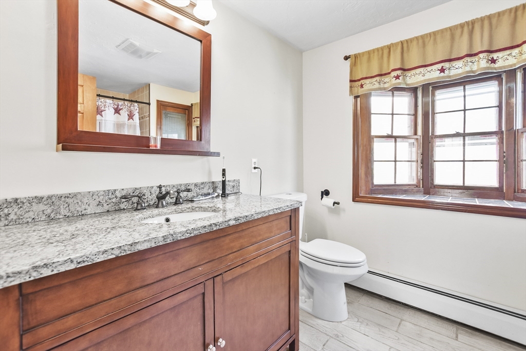 28 Adams Road Hubbardston, MA 01452 - Photo 17 of 35 a bathroom with a granite countertop sink a toilet and a window