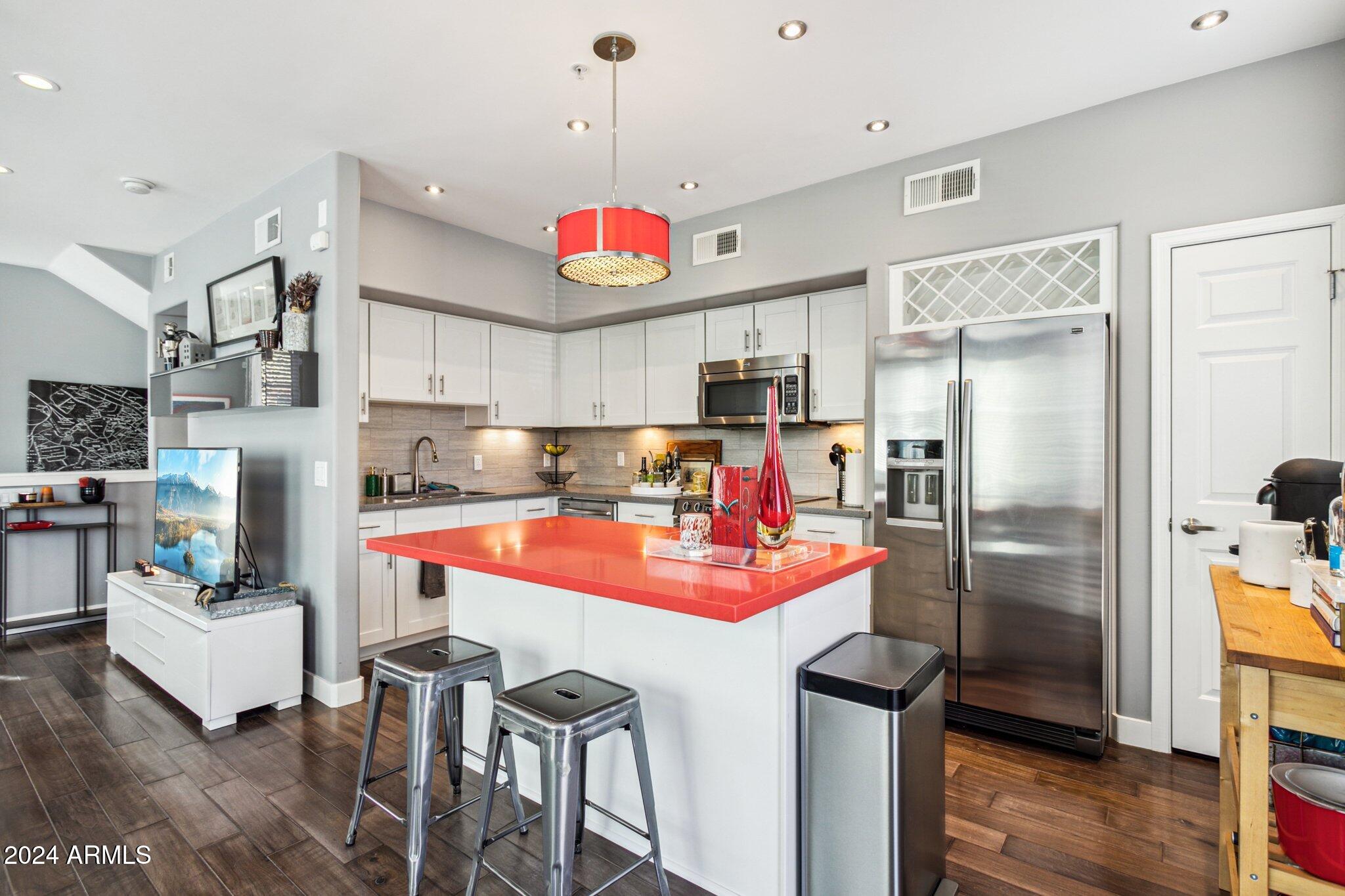 1920 East Bell Road, Unit 1161 Phoenix, AZ 85022 - Photo 8 of 37 a kitchen with stainless steel appliances kitchen island granite countertop a refrigerator a stove top oven a sink dishwasher and a dining table with wooden floor