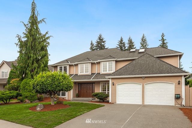 a front view of a house with a garden and trees