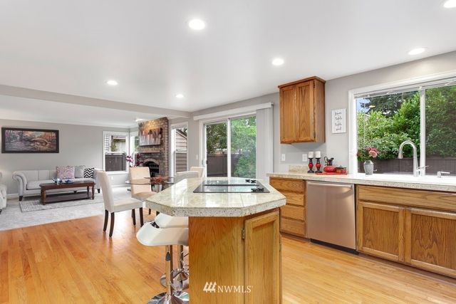 a kitchen with stainless steel appliances granite countertop a stove a sink dishwasher and a dining table with garden view