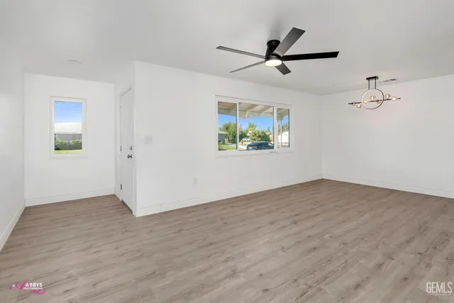 a view of empty room with wooden floor and ceiling fan
