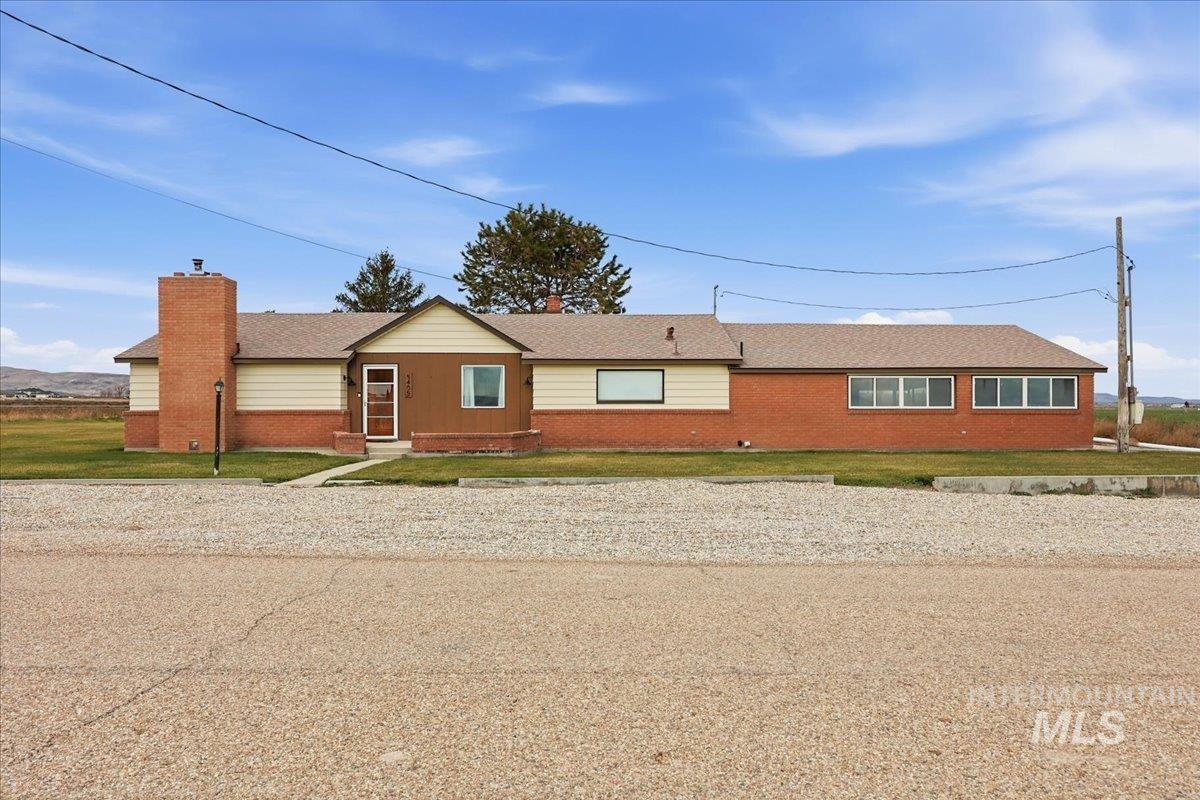 Single story home featuring brick siding, a front yard, a chimney, and a shingled roof