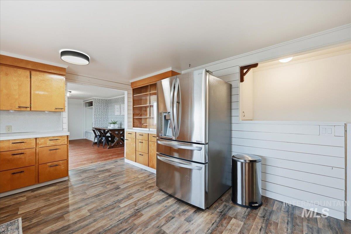 5405 Hogg Road Homedale, ID 83628 - Photo 13 of 29 Kitchen with stainless steel refrigerator with ice dispenser, light countertops, dark wood-style flooring, ornamental molding, and brown cabinets