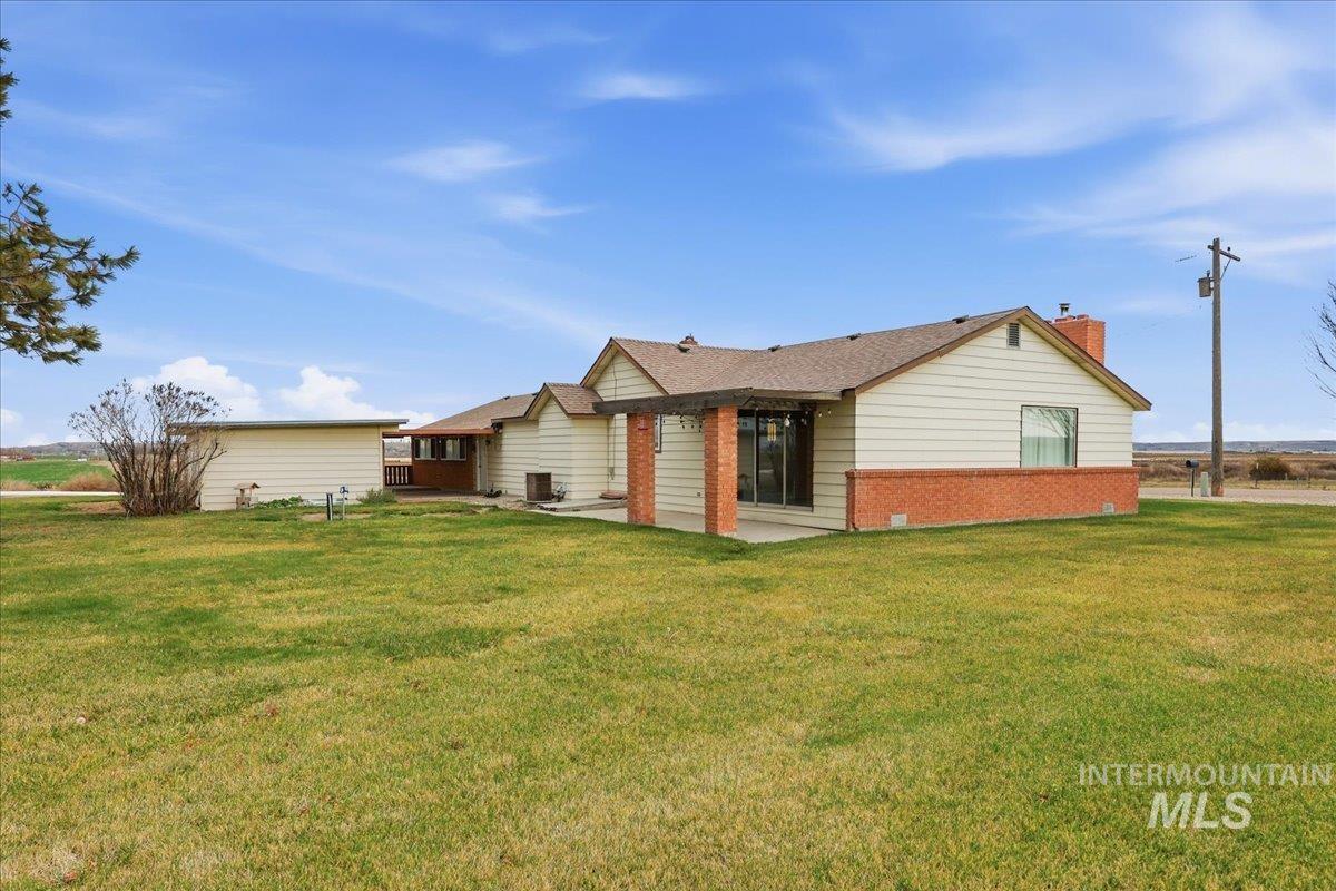 5405 Hogg Road Homedale, ID 83628 - Photo 27 of 29 Back of house with brick siding, a lawn, a chimney, and a patio area