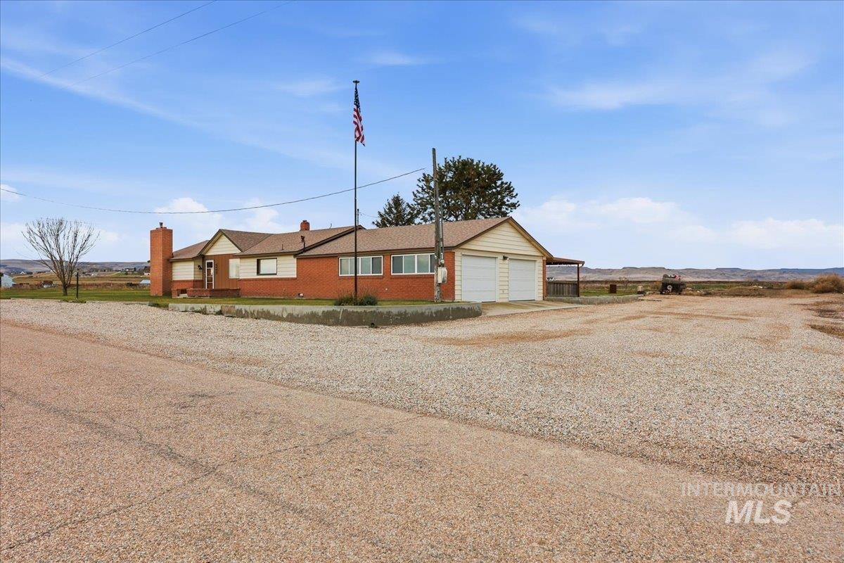 5405 Hogg Road Homedale, ID 83628 - Photo 28 of 29 View of front of house featuring gravel driveway, a chimney, brick siding, and a garage