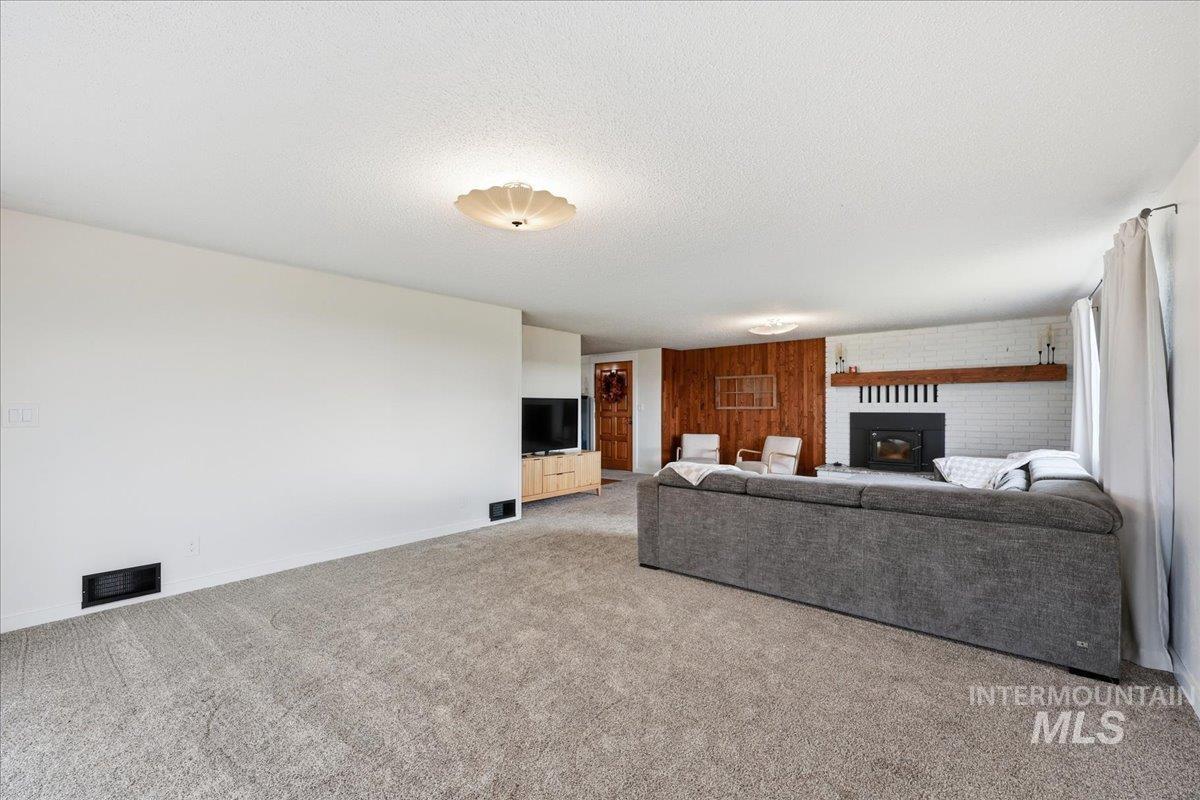 5405 Hogg Road Homedale, ID 83628 - Photo 7 of 29 Living room featuring a textured ceiling, carpet, a fireplace, and wooden walls