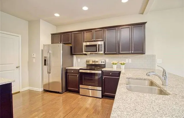 a kitchen with stainless steel appliances granite countertop a refrigerator stove and sink