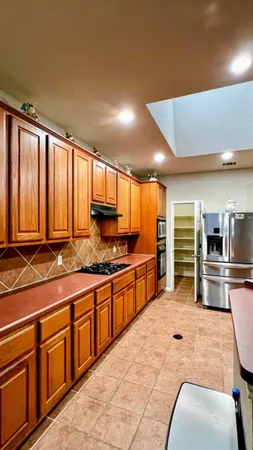 a large kitchen with stainless steel appliances a large counter top a stove a sink and a refrigerator