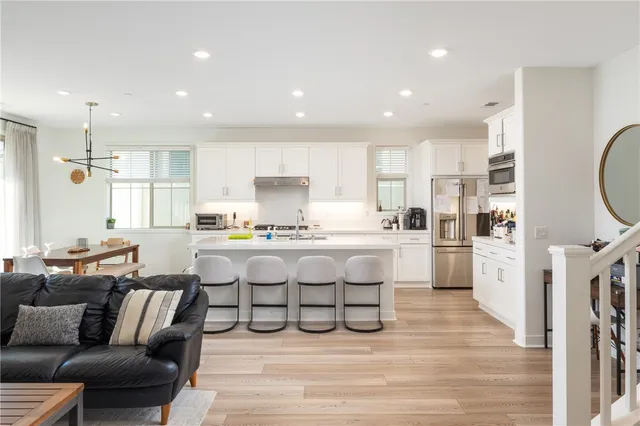 a living room with white furniture and kitchen view