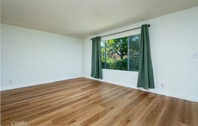 a view of a big room with wooden floor and windows