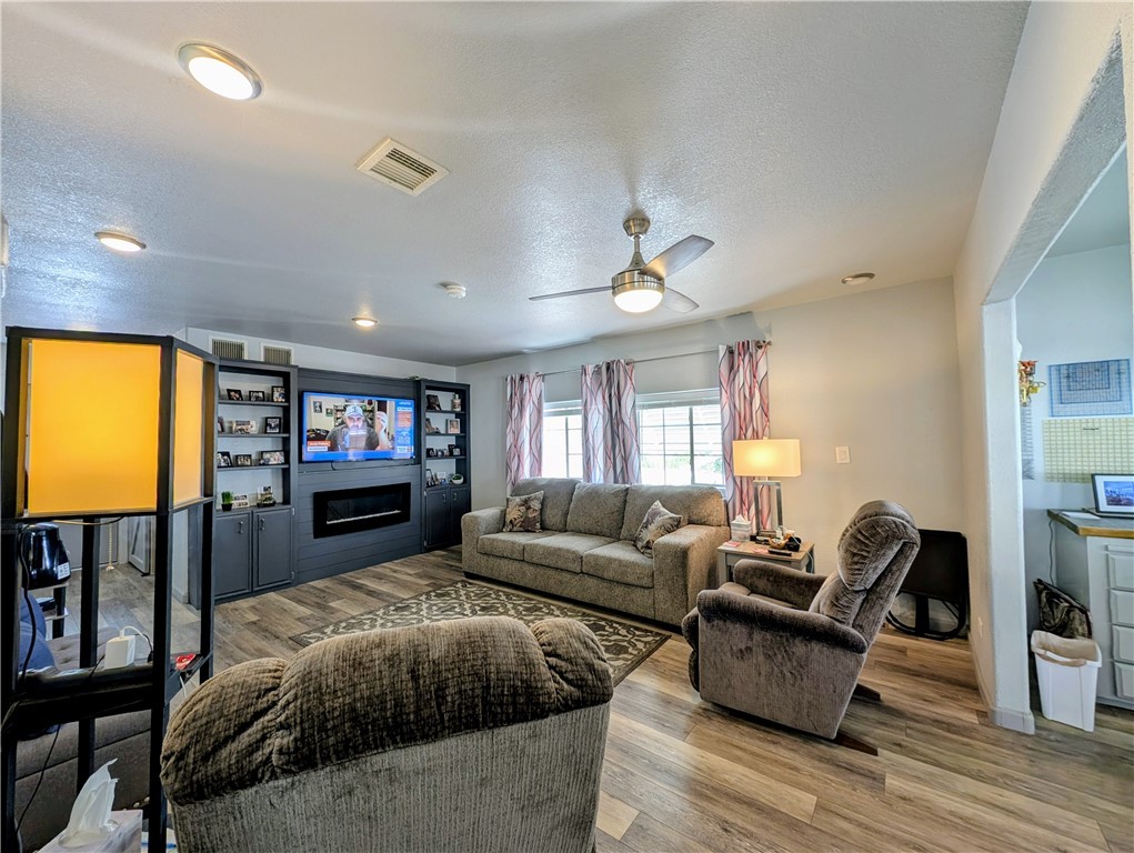 2000 Ramar Road, Unit 442 Bullhead City, AZ 86442 - Photo 13 of 28 Living area featuring a textured ceiling, wood finished floors, a glass covered fireplace, and a ceiling fan