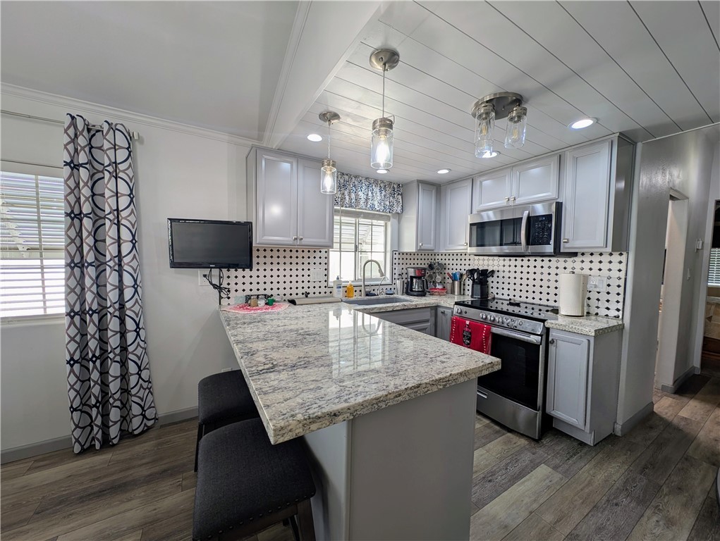 2000 Ramar Road, Unit 442 Bullhead City, AZ 86442 - Photo 15 of 28 Kitchen featuring gray cabinets, a peninsula, appliances with stainless steel finishes, decorative backsplash, and a breakfast bar area