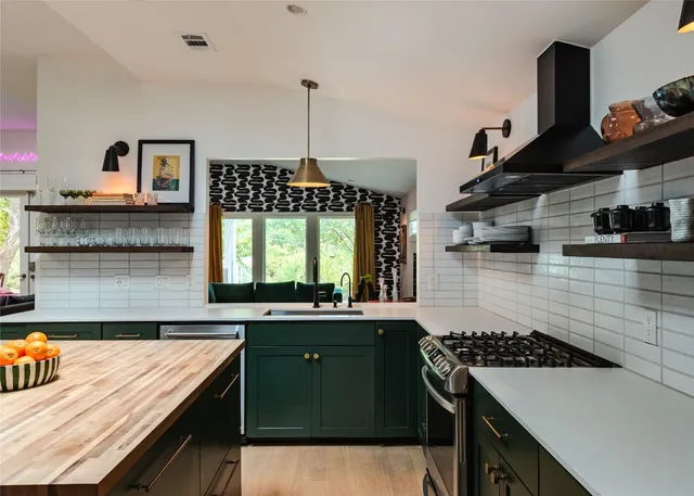 a kitchen with kitchen island stainless steel appliances a sink stove and window