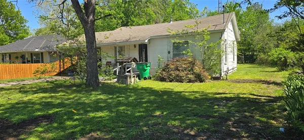 a view of a white house with a big yard and potted plants